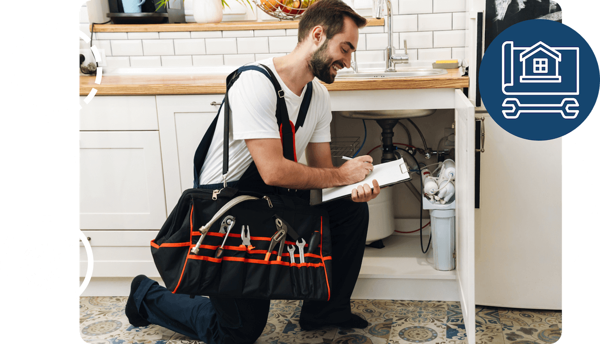 A tradesman making notes on a repair under a sink